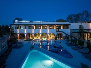 an exterior view of a building with a swimming pool at night at Bordűr Wellness Hotel Superior és Szőnyegmúzeum in Békésszentandrás