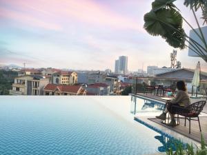 a woman sitting on a chair next to a swimming pool at Mandala Hotel & Spa Bac Ninh in Bắc Ninh +119 photos