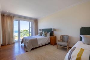 Un dormitorio con una cama y una silla y una ventana. en 22 Sewell Street, en Plettenberg Bay