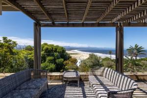 un porche cubierto con 2 sofás y una mesa en 22 Sewell Street, en Plettenberg Bay