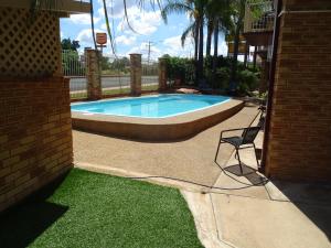 a swimming pool with a chair next to a house at Tallarook Motor Inn in Dubbo
