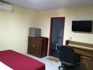 a bedroom with a bed and a desk and a television at Jessies beach house in Pulau Lutung
