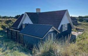 a house with a black roof with a horse standing next to it at Holiday Home Fanø 24 in Fanø +8 photos