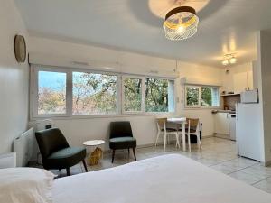 a bedroom with a bed and chairs and a kitchen at Studio cosy Tours-Sud in Tours