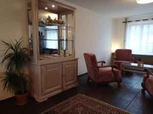 a living room with a large wooden cabinet and two chairs at Guesthouse La maison de Fille in Diest