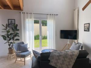 a living room with a couch and a sliding glass door at Terres de Nacre - Hébergement touristique & d'affaires in Ouistreham