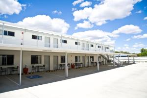 a large white building with tables and chairs at Roma Central Motel in Roma