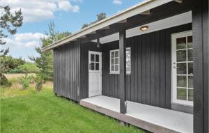 una casa negra con una puerta blanca y césped verde en Holiday Home Bjerges Toft, en Fanø 10 fotos más