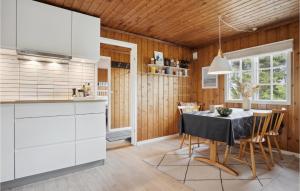 Una cocina con gabinetes blancos y una mesa con sillas. en Holiday Home Bjerges Toft, en Fanø