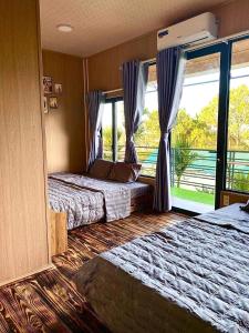 a bedroom with two beds and a large window at Đại Ngàn Homestay in Kon Von Kla