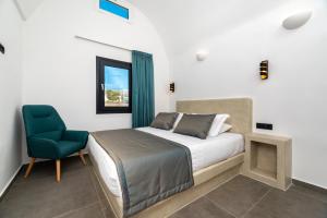 a bedroom with a bed and a blue chair at The Penthouse Santorini, Kamari, Thira in Fira +54 photos