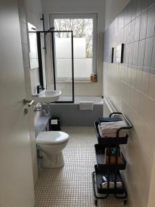 a bathroom with a toilet and a sink and a window at Direkt am Südstrand! in Wilhelmshaven