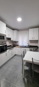 a kitchen with white cabinets and a table with chairs at Vivienda Mirasierra in Béjar