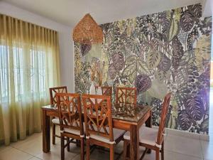 a dining room with a table and chairs and a wallpaper at Villa Ti CoCo Elegant Tropical Villa with Pool and Terraces in Trou aux Biches +6 photos