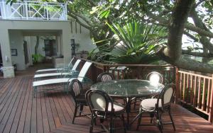 a deck with chairs and tables and a tree at Deck on Sea, 131 Nkwazi drive, Zinkwazi in Zinkwazi Beach