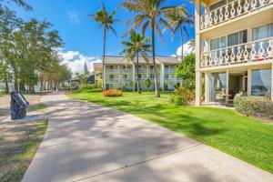 a walkway in front of a building with palm trees at Islander on the Beach 154 in Kapaa