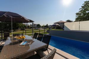 a table with a bowl of fruit and an umbrella at Casa Levant in Funtana