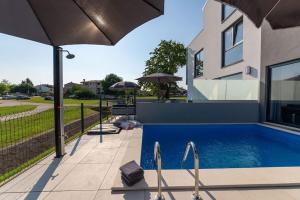 a house with a swimming pool with an umbrella at Casa Levant in Funtana