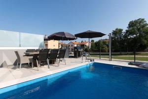 a patio with a table and chairs and umbrellas next to a pool at Casa Levant in Funtana