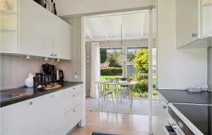 Una cocina con gabinetes blancos y una mesa con sillas. en Two-Bedroom Holiday Home In Tisvildeleje, en Tisvildeleje 9 fotos más