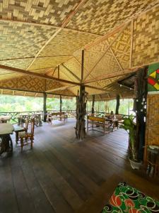 a large pavilion with tables and chairs on a wooden floor at Floating Dreams in Tangkahan