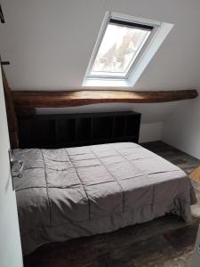 a bed in a room with a window at La Grange in Avallon