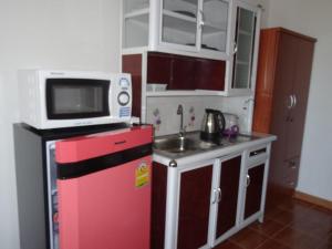 een kleine keuken met een magnetron bovenop een rode koelkast bij Rayong Condochain in Ban Phe