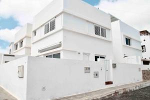 biały budynek apartamentowy z białą ścianą w obiekcie Gran terraza 1 minuto de las piscinas naturales w mieście Punta de Mujeres
