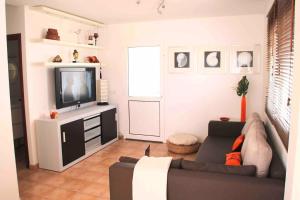 salon z kanapą i telewizorem w obiekcie Gran terraza 1 minuto de las piscinas naturales w mieście Punta de Mujeres