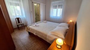 una camera da letto con un letto, una sedia e finestre di Apartment Zvone a Veli Rat