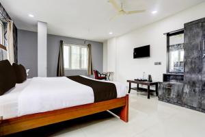 a bedroom with a bed and a desk and a television at Super Townhouse VIP Hills Hitech City in Hyderabad