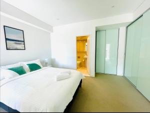 a white bedroom with a large bed and a bathroom at Astonishing waterview condo with Pool, Parking in Sydney +15 photos