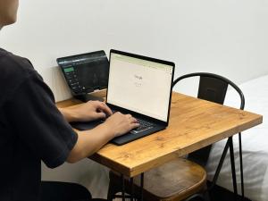 eine Person, die mit einem Laptop an einem Tisch sitzt in der Unterkunft THE BEDROOM Daimyo in Fukuoka