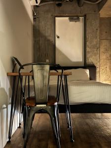 ein Stuhl und ein Schreibtisch in einem Schlafzimmer mit einem Bett in der Unterkunft THE BEDROOM Daimyo in Fukuoka