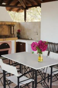 a white table with a vase of flowers on it at Vatellis Villas in Patitiri