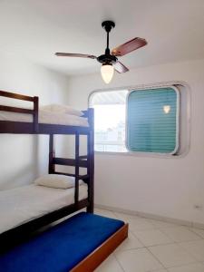 a room with two bunk beds and a ceiling fan at AO SOM DO MAR - 15 metros da praia in Guarujá
