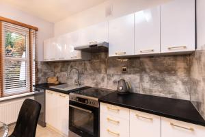 a kitchen with white cabinets and a black counter top at Domek blisko plazy in Świnoujście