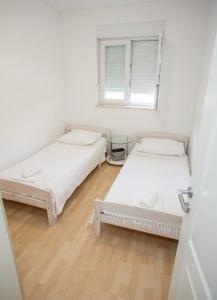 Dos camas en una habitación blanca con ventana. en Apartments Karma, en Novalja