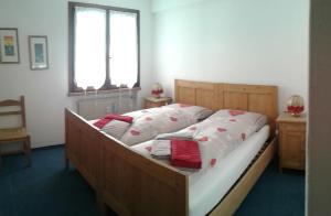 una camera da letto con letto in legno, lenzuola bianche e cuscini rossi di Appartamento Italia ad Alleghe