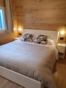 a bedroom with a large white bed with wooden walls at Alpin House Tonale in Passo del Tonale