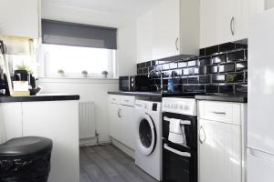 a white kitchen with a washer and dryer at Dunbank Apartment in Clydebank