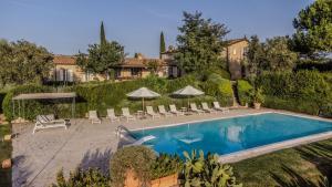 a pool in a yard with chairs and umbrellas at Villa Lotus Magliano in Magliano in Toscana
