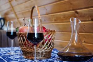 two glasses of red wine next to a basket of apples at Kvabtkari Cottages in Ambrolauri