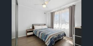 a bedroom with a bed and a large window at Holiday Rentals in Ascot Park