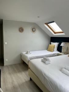 two beds in a room with white walls at Les Embruns in Trouville-sur-Mer