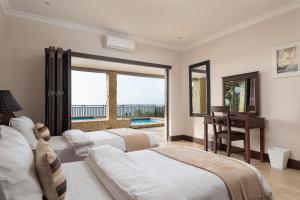 a bedroom with two beds and a desk and a balcony at Stella Road 24 in Ballito +26 photos