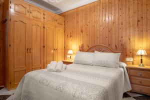 Un dormitorio con una cama blanca con paredes de madera. en Casa Bambury, en Conil de la Frontera
