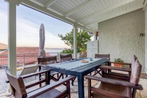 a table and chairs on a porch with a view of the ocean at Villa Angeliki by Tsiolis Family in Katávolos