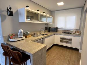 a kitchen with white cabinets and a counter top at Riviera - Sofisticado e Moderno com Enxoval Completo in Riviera de São Lourenço +36 photos