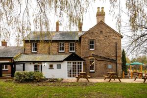 a large brick building with picnic tables in front of it at The Olde Coach House Inn in Ashby Saint Ledgers